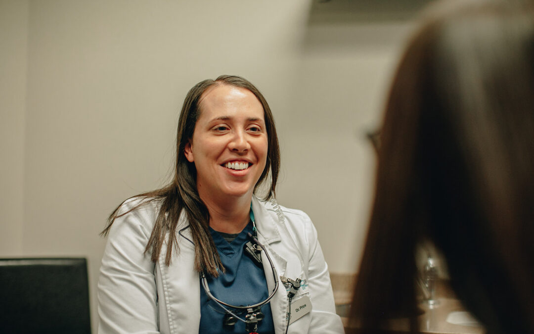 Smiling female dentist in a white coat engaging with a patient, showcasing Hometown Dental's friendly environment and commitment to patient care.